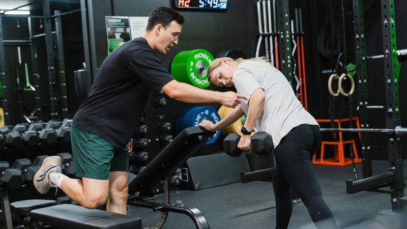 Busy professional training with a Habitat Gym coach at Prestons facility, performing a strength exercise under supervision.