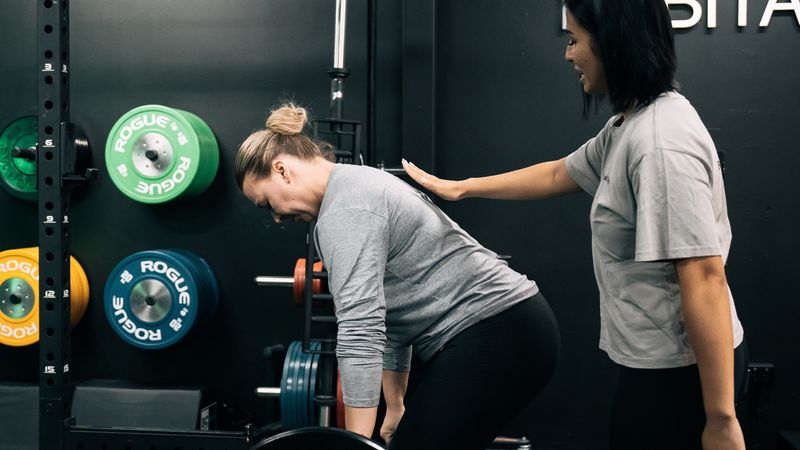 Personal trainer guiding a client during a strength training session at Habitat Gym.