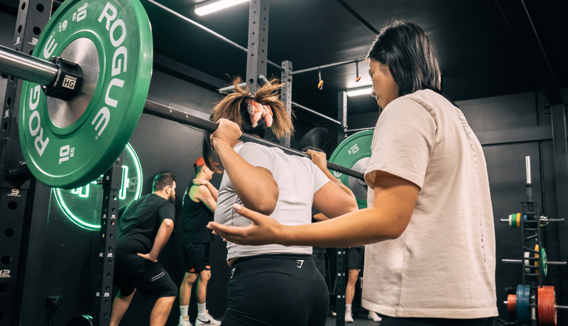 Habitat Gym coach assisting a member doing barbell squats