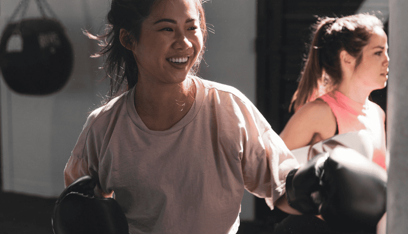 Women smiling wearing boxing gloves during an intense workout