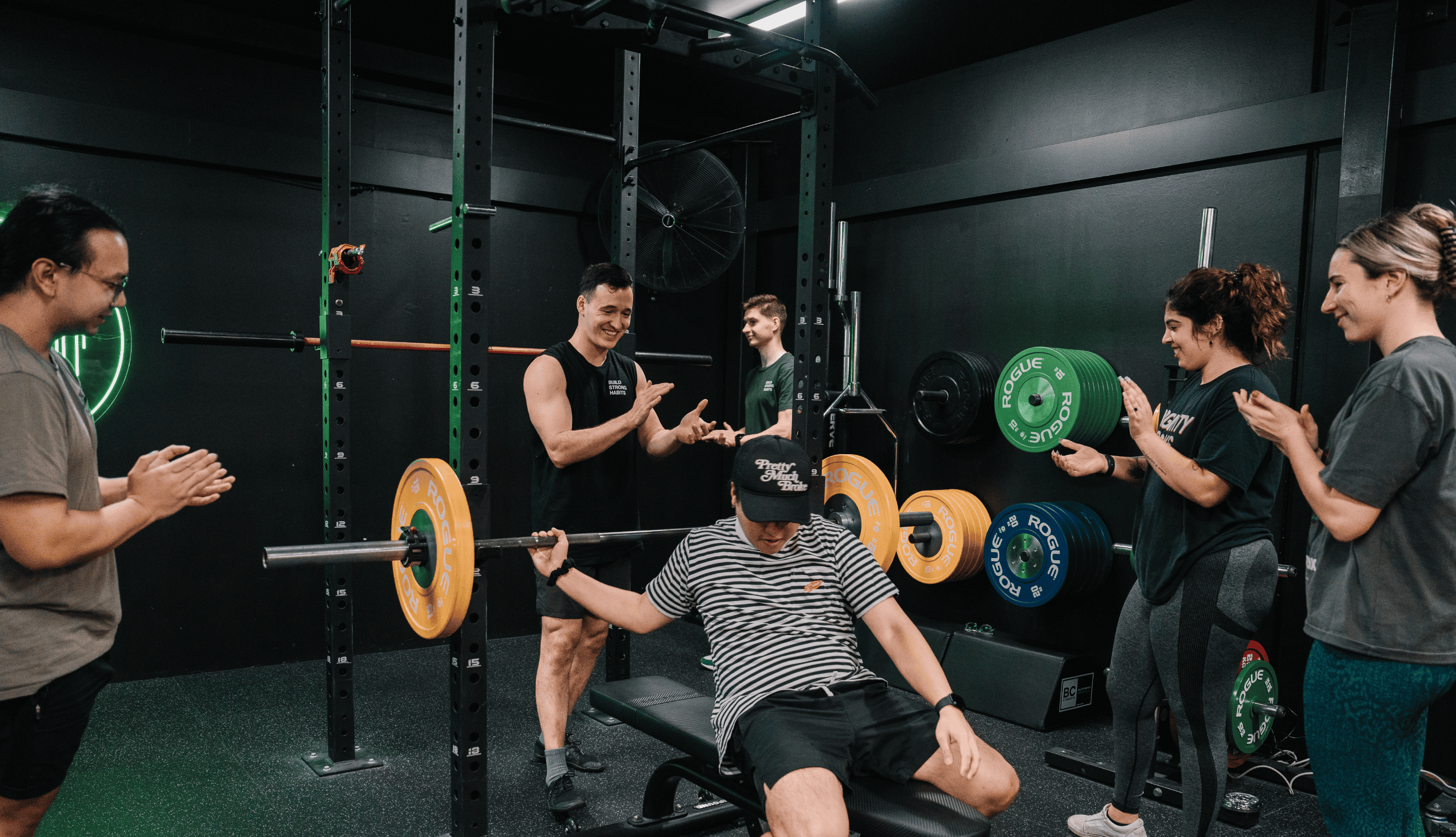 Coach and gym members cheering for a person doing bench press