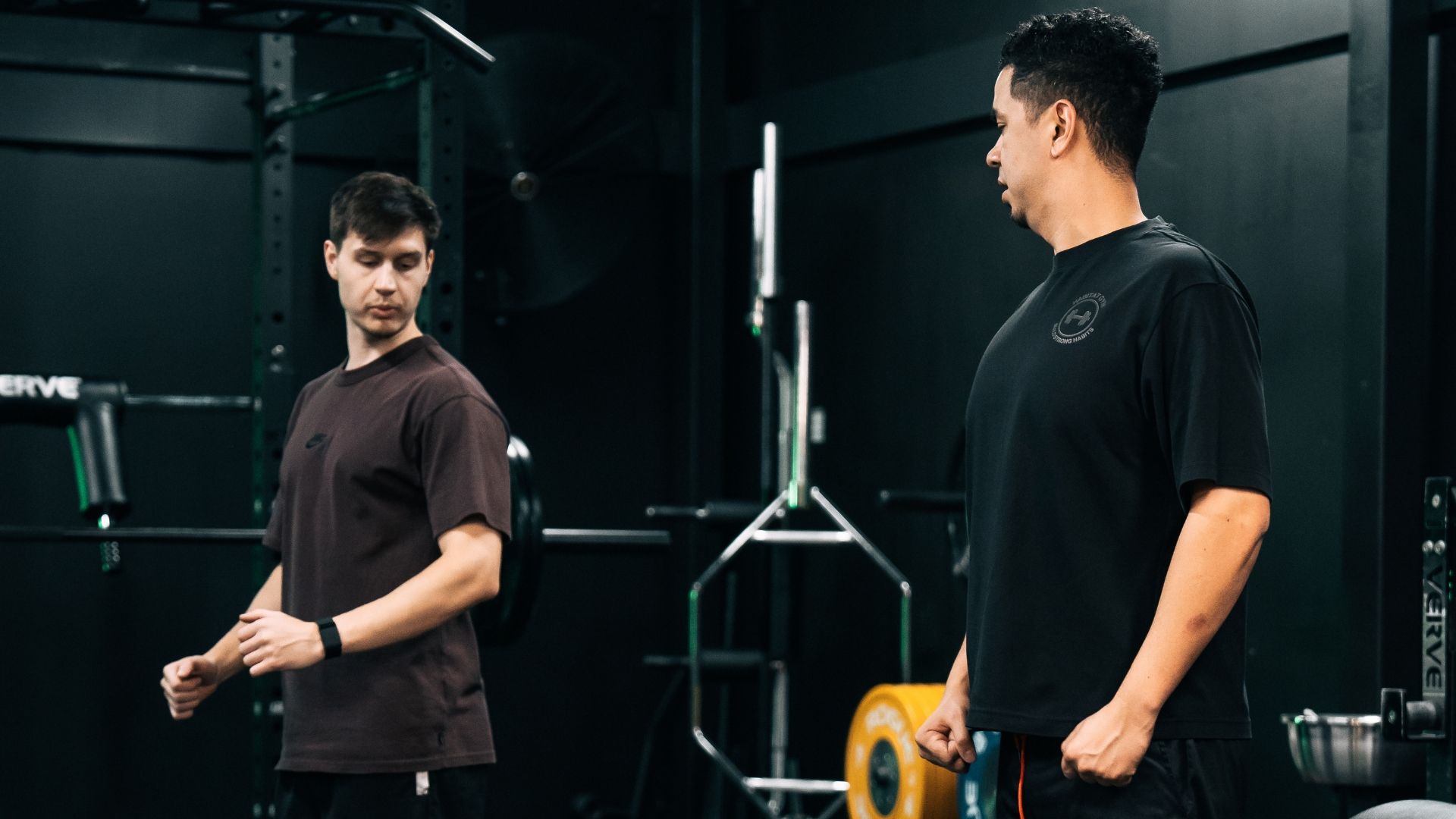 Personal trainer guiding a client during a strength training session in the gym, focusing on form and technique.