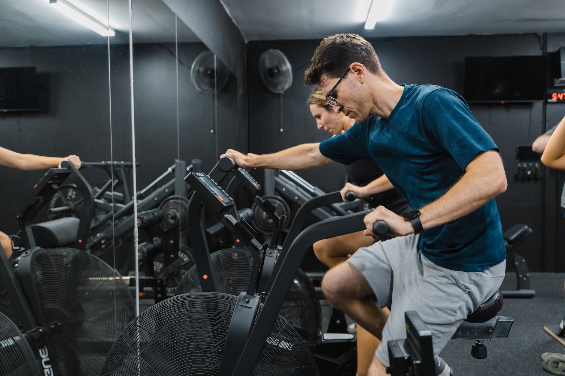 Members doing high-intensity intervals on Rogue Echo bikes at Habitat Gym