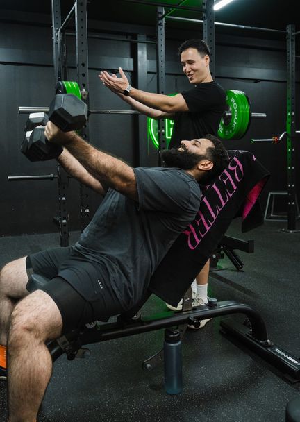 Personal trainer motivating client through weights session in local Prestons gym