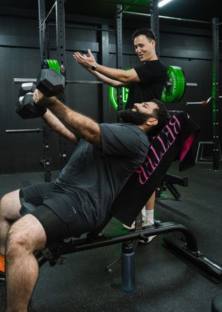 Personal trainer motivating client through weights session in local Prestons gym