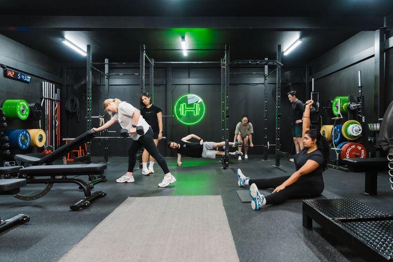 Semi-private personal training session at Habitat Gym with coach supervision, members performing strength exercises in a structured gym environment.