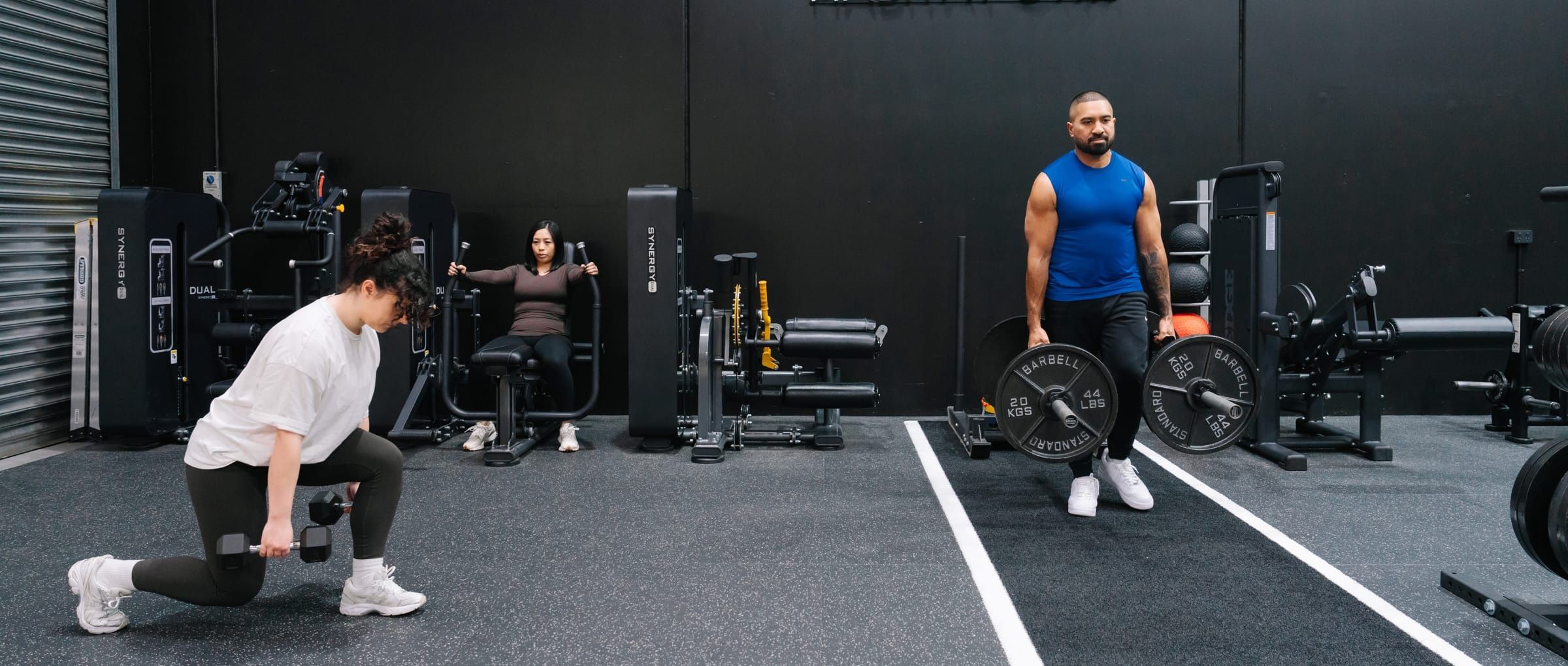 Members training across the gym floor at Habitat Gym in Prestons, dumbbell lunges in the foreground