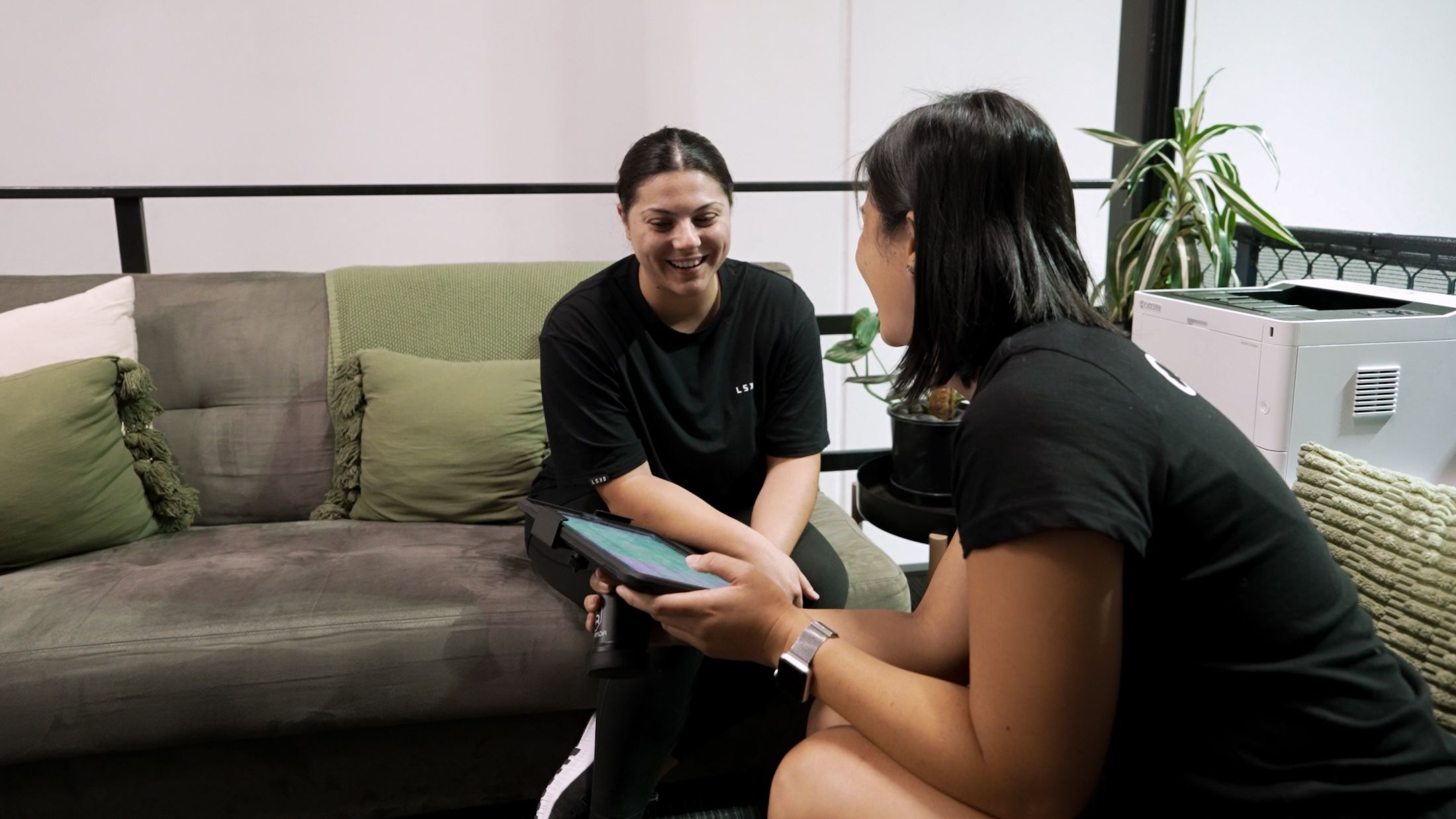Coach and member sitting down on couch discussing nutrition planning on an ipad inside Habitat Gym