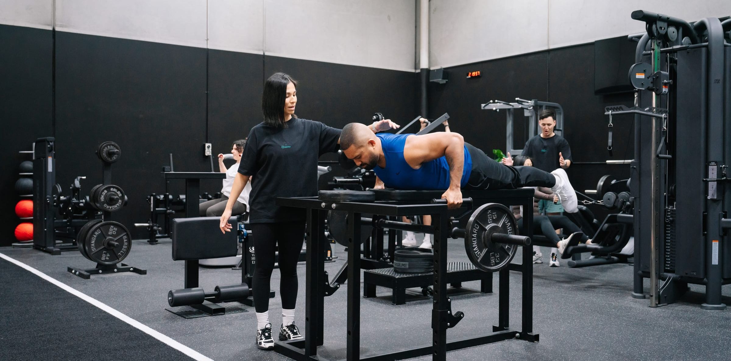 Coach guiding a client through chest-supported barbell rows on a raised bench at Habitat Gym in Prestons