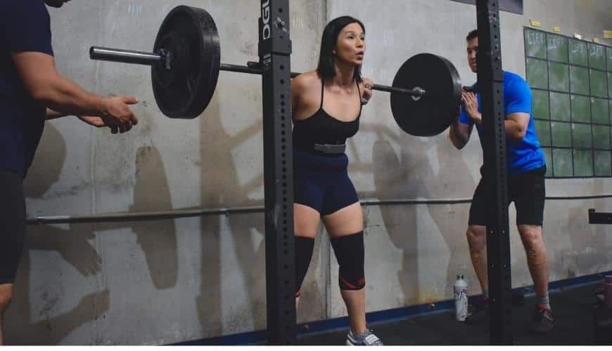 Coach Jeannie doing barbell back squats at a weightlifting competition