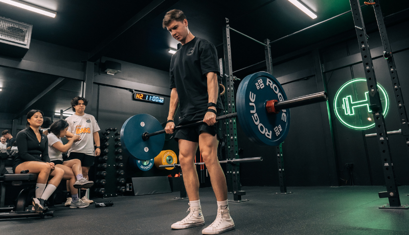Man deadlifting at Habitat Gym while other members watch
