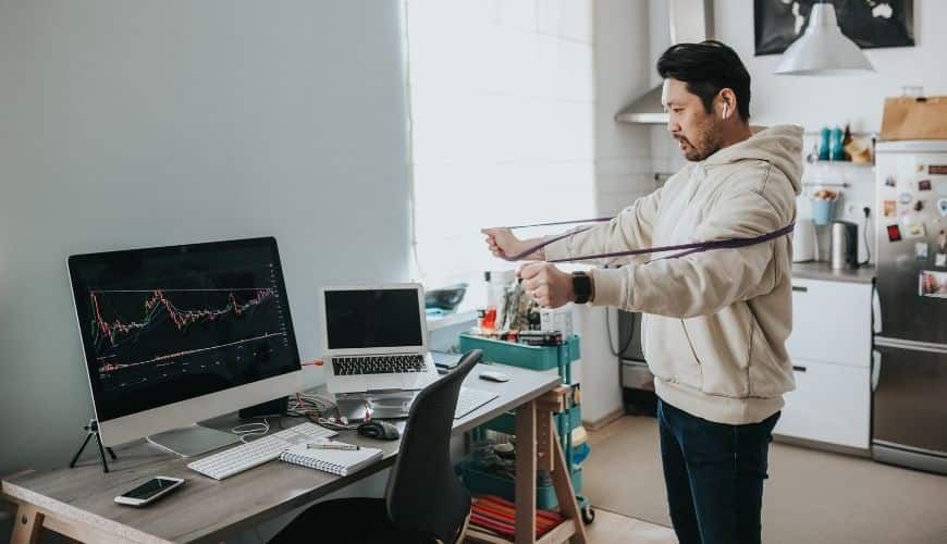 Man stretching at desk to improve posture and reduce back pain from long hours sitting