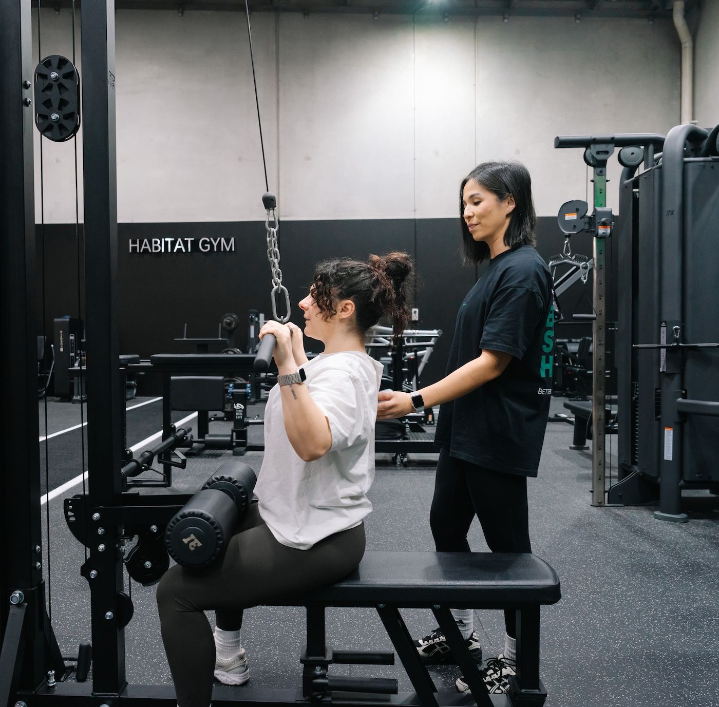 Coach guiding a member through lat pulldowns during a personal training session at Habitat Gym