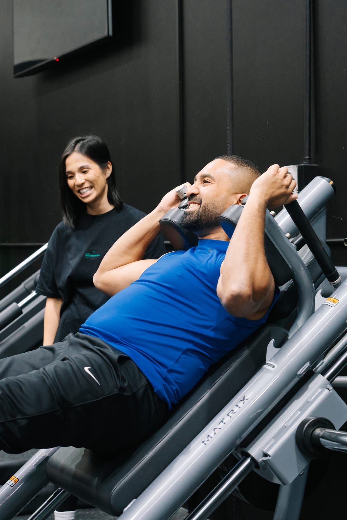 Coach coaching a member through a set on the Matrix hack squat machine at Habitat Gym