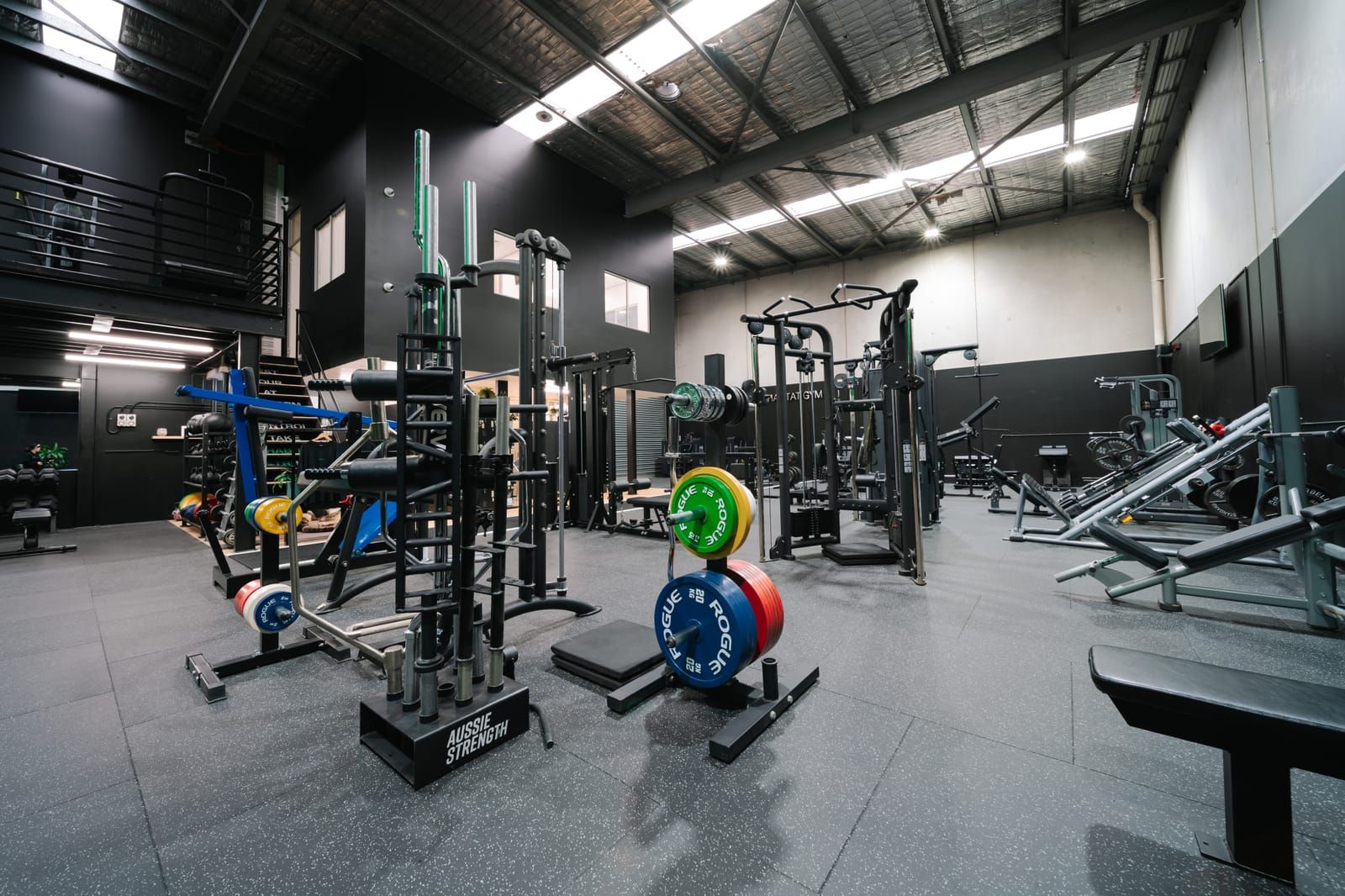 Colourful competition bumper plates stacked on toaster racks among the plate-loaded machines