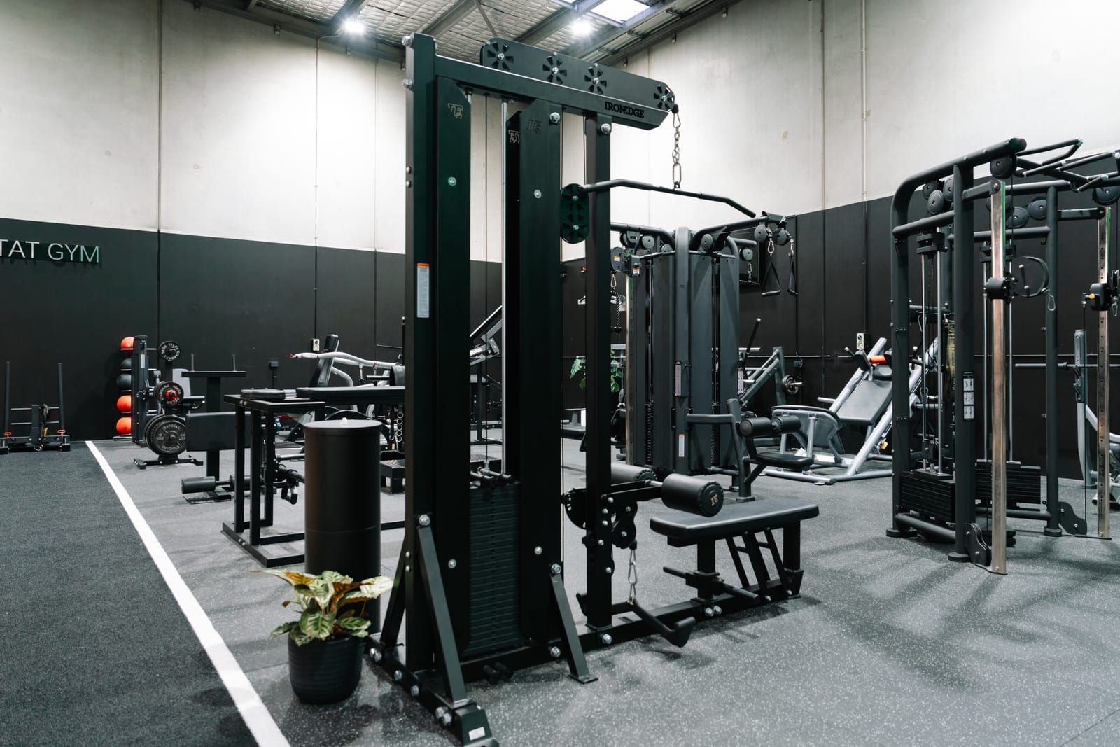 Multi-station cable machine with a seated row bench among the machines at Habitat Gym