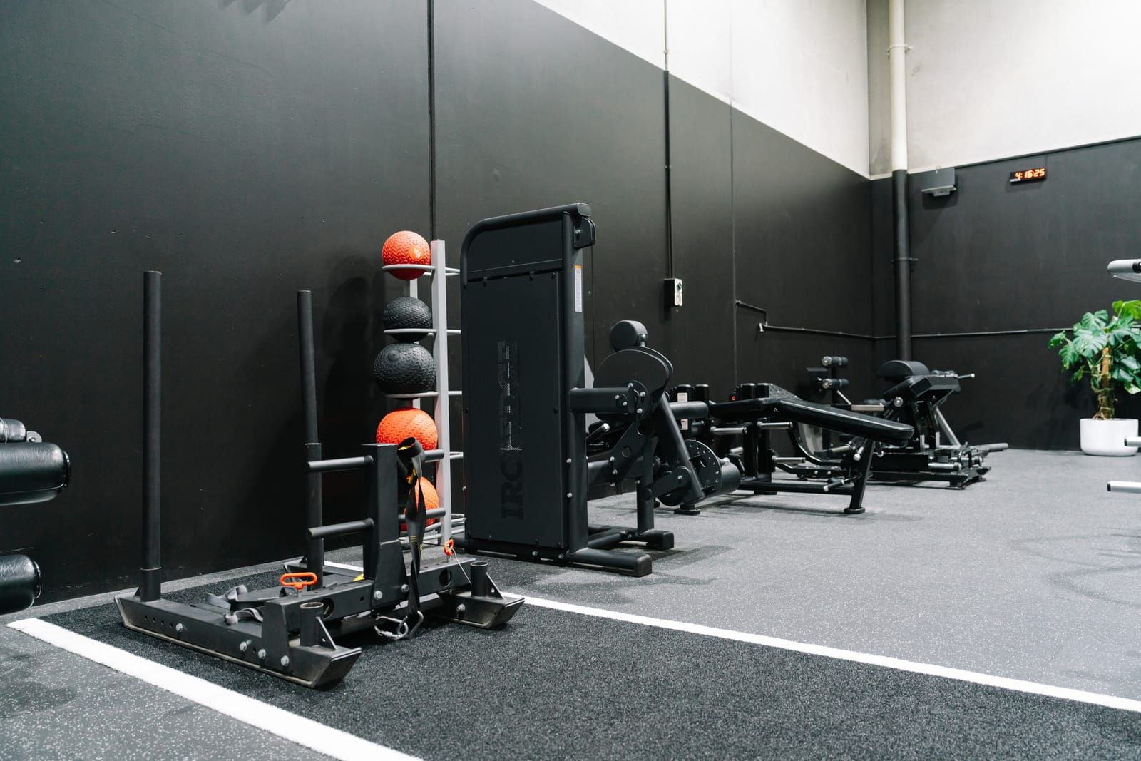 Weight sled and stacked slam balls beside the turf strip in Habitat Gym’s strength zone
