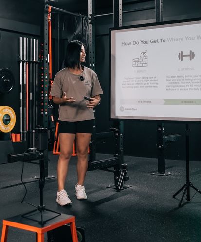 Coach Jeannie presenting the Build Strong Habits framework during a workshop at Habitat Gym, with the Build and Strong roadmap on the projector screen