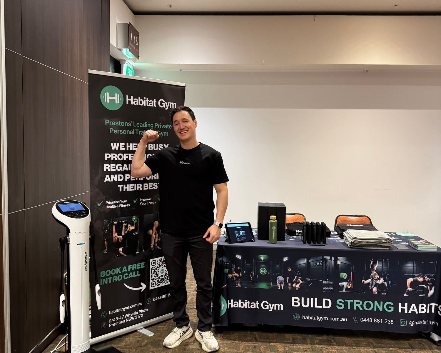 Coach standing beside Habitat Gym’s ‘Build strong habits’ banners at the South West Entrepreneurial Hub expo stand